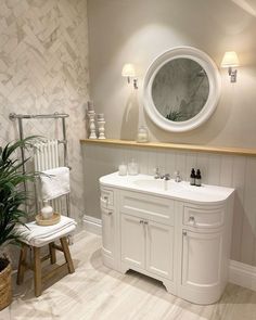 a bathroom with white fixtures and wood accents, including a round mirror above the sink