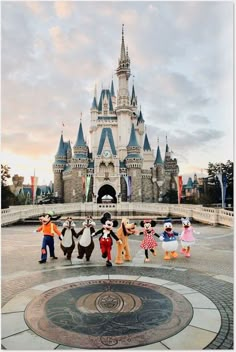 some people are dancing around in front of a castle with mickey mouses on it