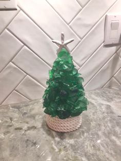 a small green christmas tree sitting on top of a counter next to a light switch