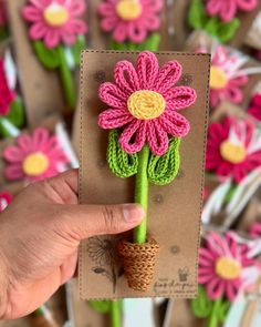 a hand holding up a flower made out of yarn