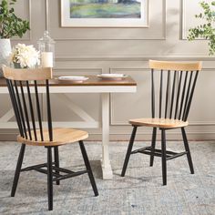 two wooden chairs sitting next to each other on top of a rug