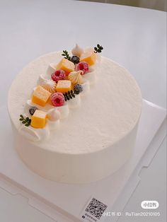 a white cake topped with fruit on top of a table