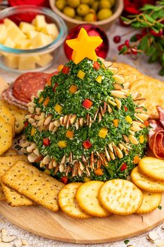 a christmas tree shaped cheese platter with crackers and olives on the side