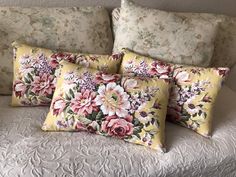 three floral pillows on a white bed