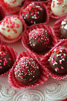 chocolates with sprinkles are on a white and red plate, ready to be eaten