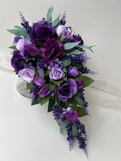 a bridal bouquet with purple flowers and greenery