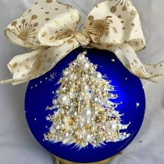 a blue ornament with a gold and white christmas tree on it's side