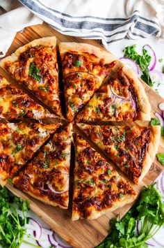 a sliced pizza sitting on top of a wooden cutting board next to green onions and cilantro