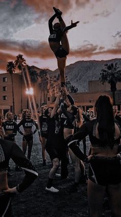 a group of cheerleaders are performing in front of a crowd at sunset with the sun setting behind them