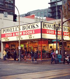 people walking on the sidewalk in front of a book store at an intersection with traffic lights