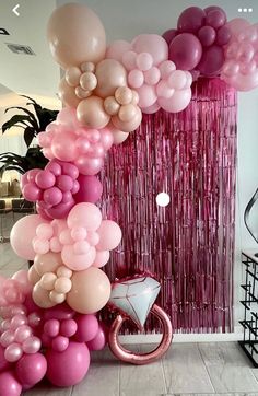 pink and white balloons are hanging from the ceiling