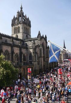 a large group of people walking in front of a building with a flag on it