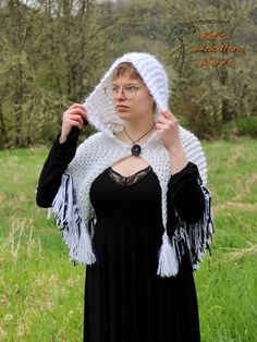 This super cozy hooded shawl is very soft and features three tassels, one on each of the three points and lots of fringe! It can be worn with any outfit and includes a coconut button to keep it secured around your shoulders. It's perfect for any woodland fairy, or elven princess, who needs an extra layer during the autumn and winter months! Color: White and Black Materials: Yarn (acrylic, wool, nylon, metalic, and other fibers), coconut button Size: One-size-fits-most Hood Length (hood front to White Fringed Winter Shawl, White Fringe Shawl For Winter, White Fringed Shawl For Winter, Hooded Shawl, Elven Princess, Mind Palace, Fringe Shawl, Woodland Fairy, Knitted Shawls