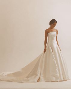 a woman in a white wedding dress is posing for the camera with her long train