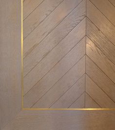 an empty wooden door with gold trim on the bottom and side panel, in a herringbone pattern