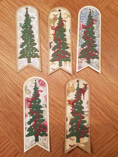 four tags with christmas trees on them sitting on a wooden table next to each other