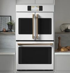 two ovens side by side in a kitchen with white cabinets and gray countertops