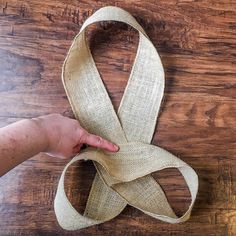 someone is holding a piece of jute ribbon on a wooden floor with their hand