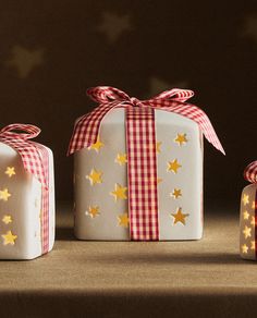 three wrapped presents with gold stars on them, one white and the other light up