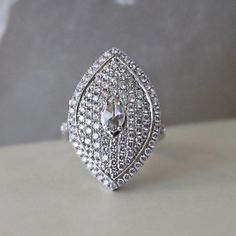 a diamond ring sitting on top of a white table next to a gray wall,