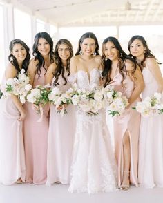 a group of women standing next to each other holding bouquets in their hands and smiling at the camera