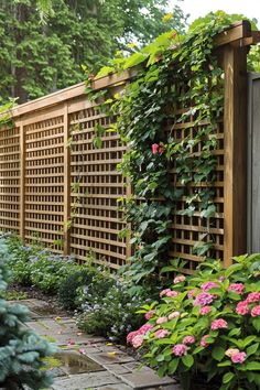 an outdoor garden with flowers and plants growing on the side of it, next to a wooden fence