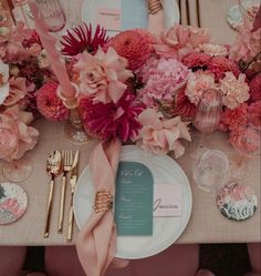 the table is set with pink flowers and place settings