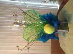 a tennis ball is in the center of a vase with blue ribbon and star decorations