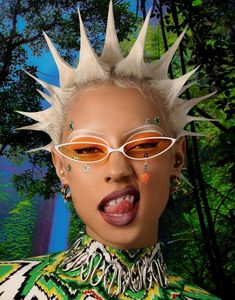 a woman with spiked hair and glasses in front of a forest background, wearing an unusual outfit