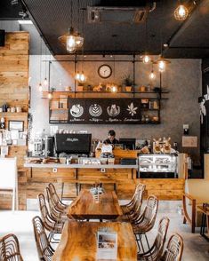 the interior of a restaurant with wooden tables, chairs and lights hanging from the ceiling