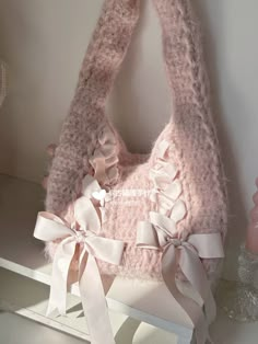 a pink handbag with white bows on it sitting on a shelf next to a vase