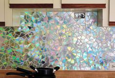 a stove top oven sitting next to a window covered in iridescent glass tiles