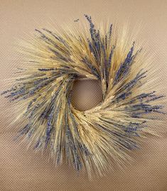 a close up of a wreath made with blue and yellow flowers on a tan background