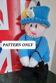 a small knitted doll sitting on top of a table next to a british flag