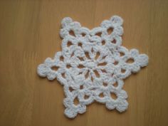 a white crocheted snowflake sitting on top of a wooden table