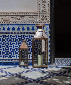 two lanterns sitting on top of a blue and white tile floor next to each other