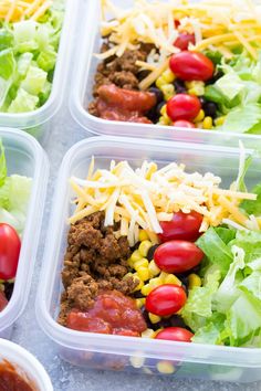 four plastic containers filled with taco salads and lettuce, tomatoes, corn, black beans, cheese