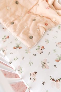 a baby crib with pink and white sheets on it's sides, next to a blanket