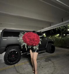 a woman walking towards a black jeep with a red flower bouquet on it's head