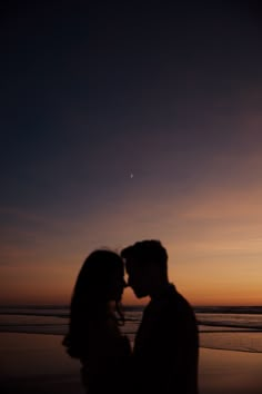 a couple kissing on the beach at sunset