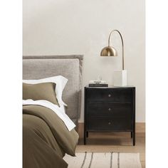 a bedroom with a bed, night stand and lamp on the nightstand next to it