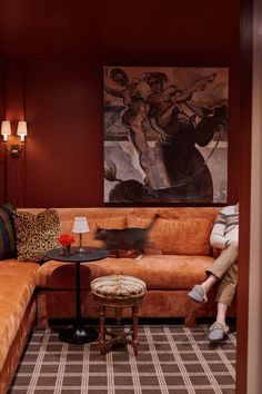 a woman sitting on a couch in a living room next to a table and lamp