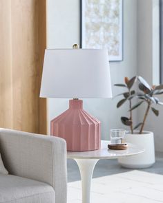 a pink lamp sitting on top of a table next to a chair