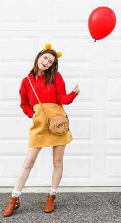 a woman in winnie the pooh costume holding a red balloon