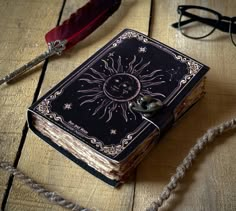 an open book sitting on top of a wooden table next to a feather quill