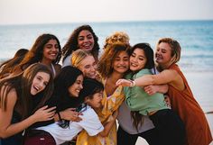 a group of young women hugging each other on the beach