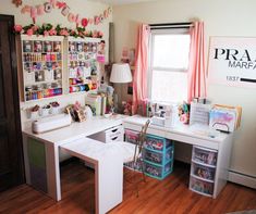 a white desk topped with drawers under a window next to a wall filled with books