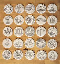 a collection of buttons with drawings on them sitting on top of a wooden table next to each other