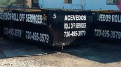 two large black dump trucks parked in front of a blue building with advertisements on them