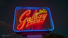 a neon sign with the word galaxy diner on it's side in front of a dark sky